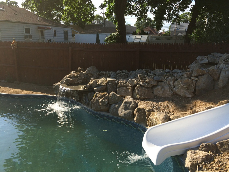 Swimming pool with rock waterfall and white slide.