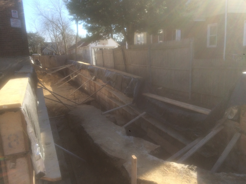 Construction site with wooden forms, braces, and a partially dug trench.