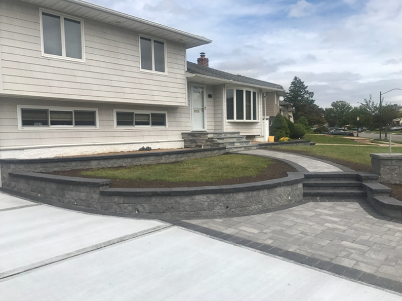 House exterior with retaining wall, paved path, and steps leading to the front door.