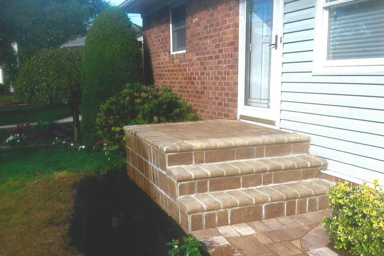 Brick steps leading up to a house entrance, with brick facade and landscaping.