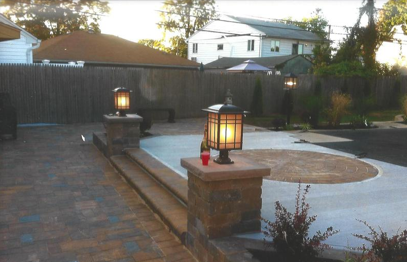 Backyard patio with stone columns, steps, and decorative lights.