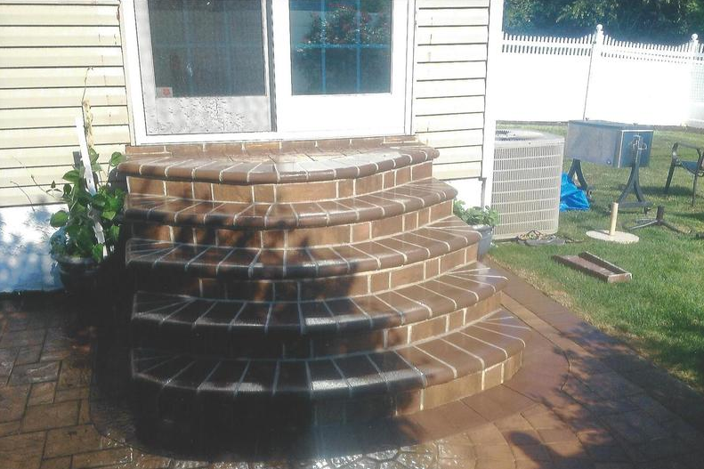 Brick steps leading up to a house door; brown brick, sunlight.