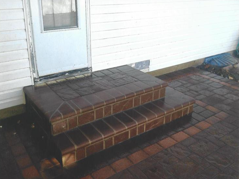 Brick steps leading to a white door, set on a brick patio.