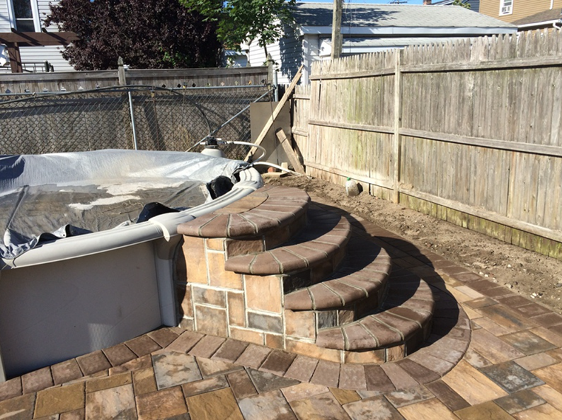 Brick pool steps next to a wooden fence and covered pool.