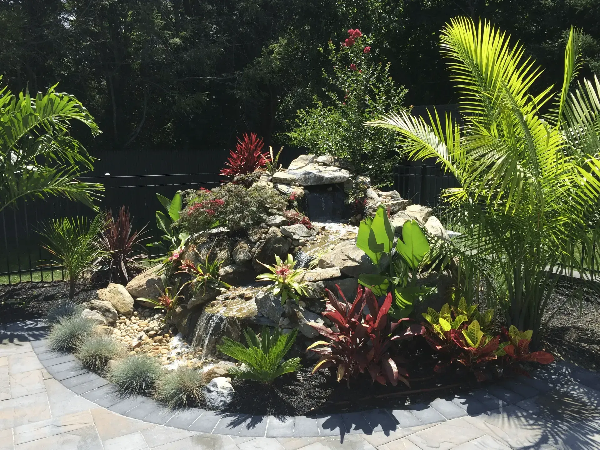 A landscape design of a lush green garden with a waterfall in the middle