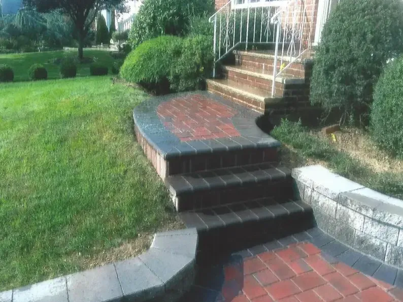 Brick steps lead to a house entrance, bordered by a brick walkway and lawn.