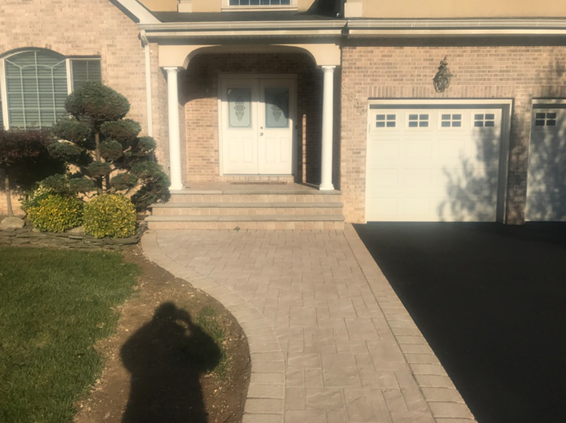 Brick house with paved walkway leading to the front door; a driveway is on the right.