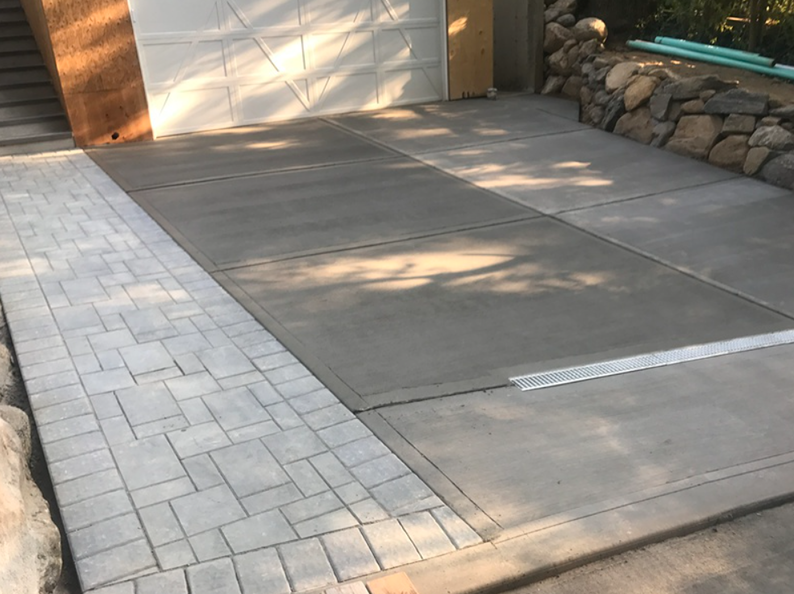 Concrete driveway with paver border, leading to a garage.