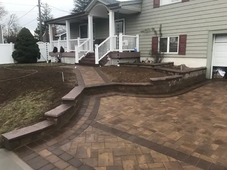 Front of a house with a brick paved walkway, steps, and a retaining wall.