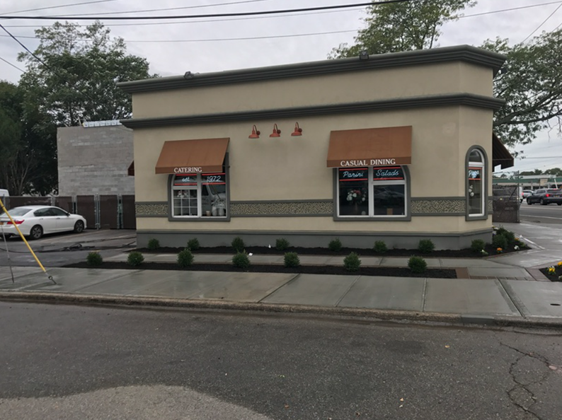 A tan floral shop with brown awnings and a small garden, located on a city street.