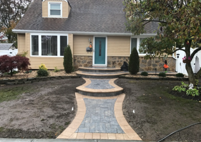 Tan house with blue door and brick pathway leading to entrance.