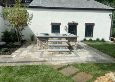 Stone hot tub with steps, patio, and green grass in a backyard setting.