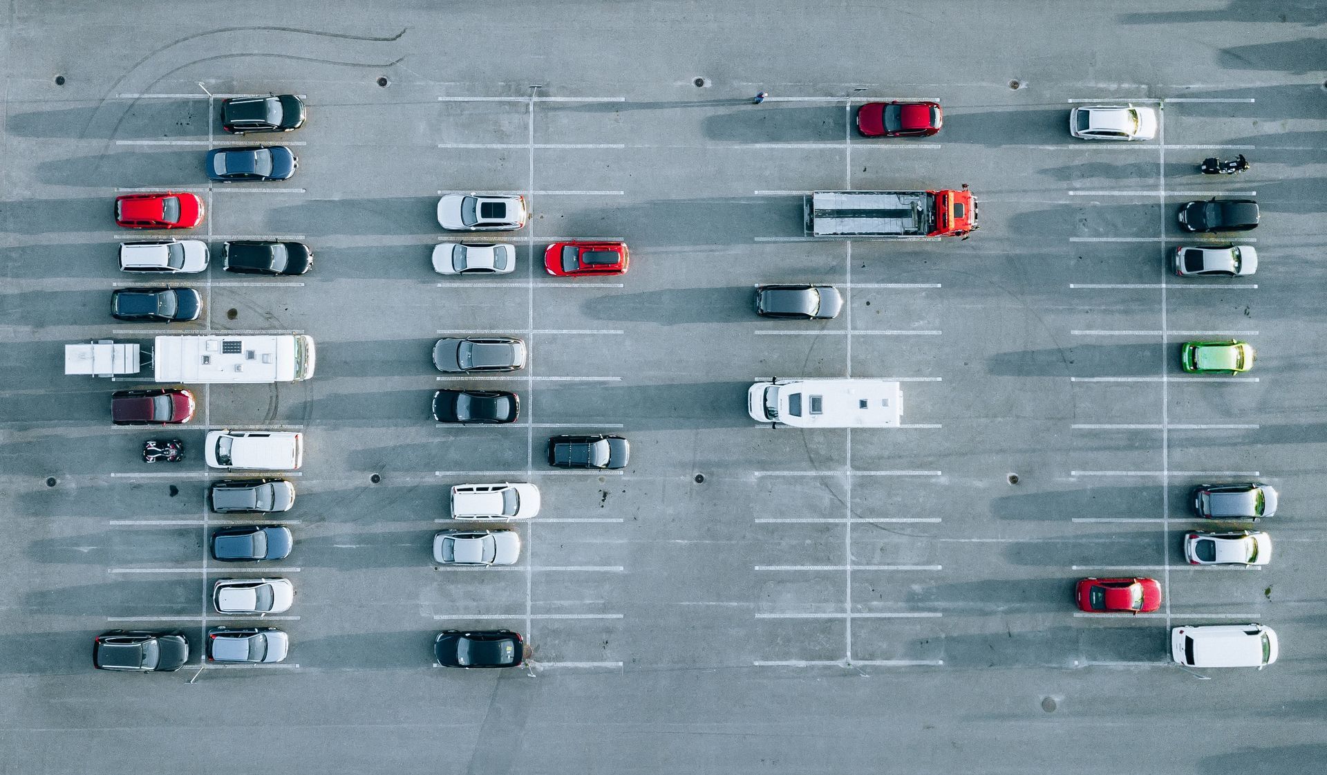 An aerial view of a parking lot filled with cars and trucks.