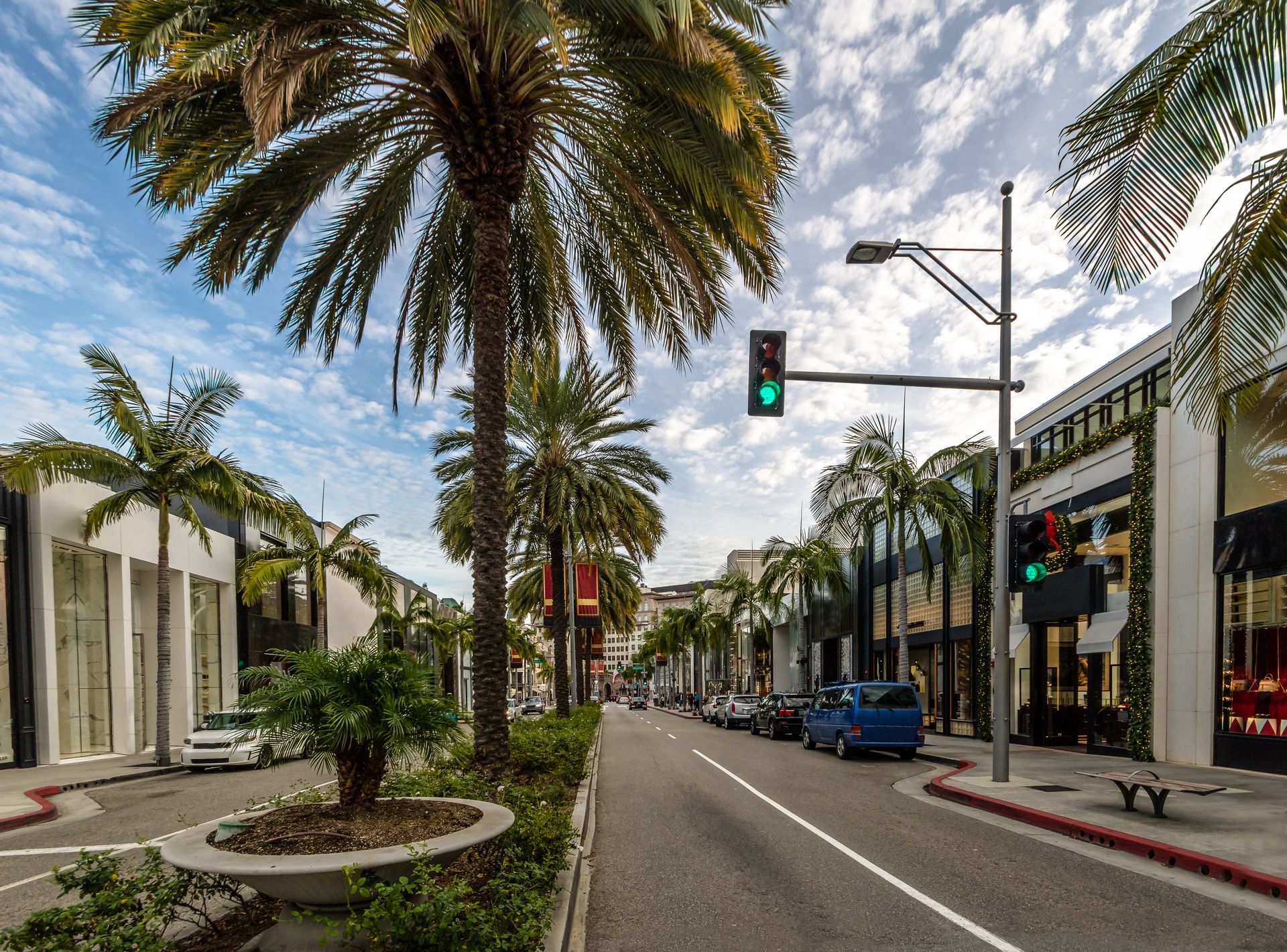A street with palm trees on the side of it and a traffic light.
