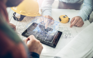 A group of construction workers are looking at a blueprint on a tablet.