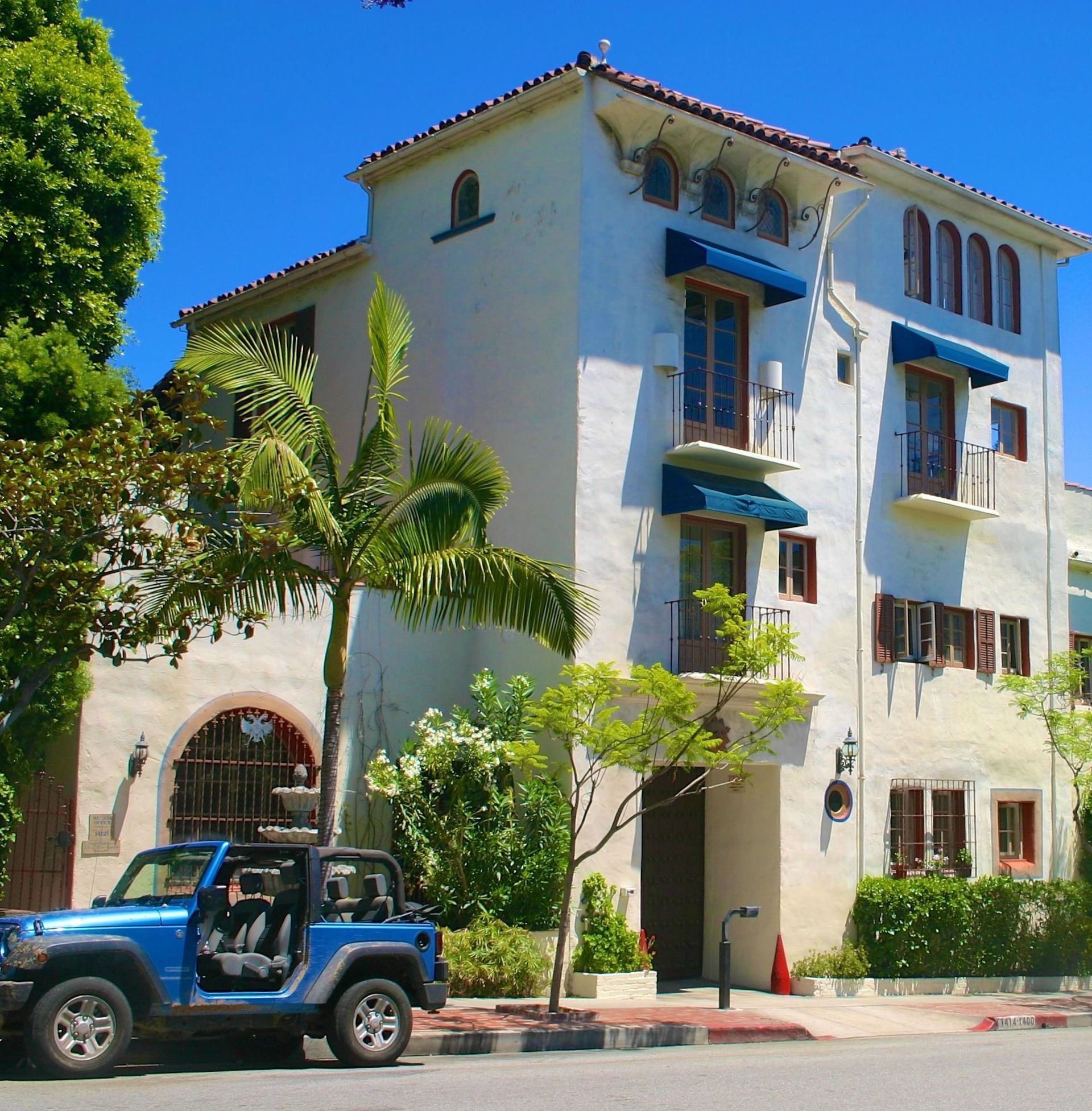 A blue jeep is parked in front of a white building