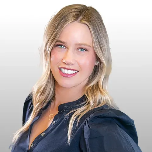 A woman is wearing a blue tank top and looking at the camera.
