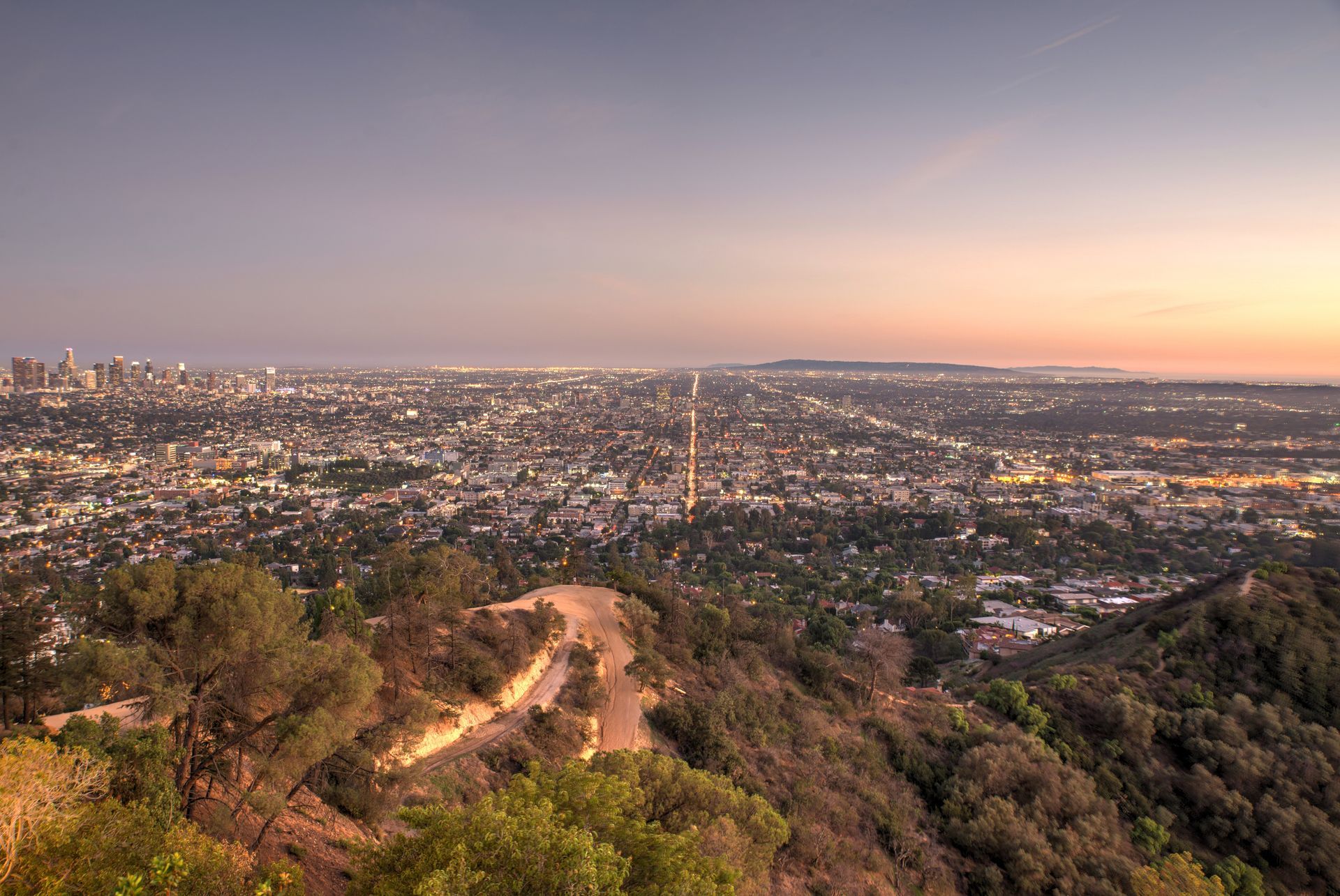 A view of a city from a hill at sunset.