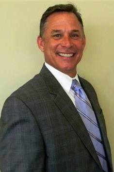 A man in a suit and tie is smiling for the camera.