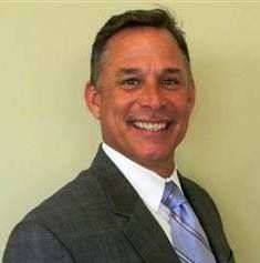 A man in a suit and tie is smiling for the camera.