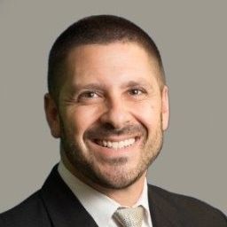 A man in a suit and tie is smiling for the camera.