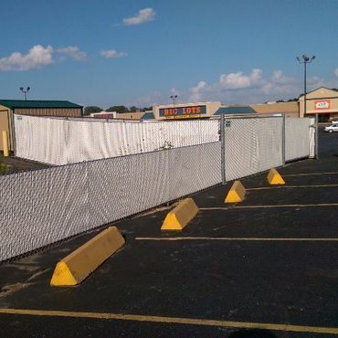 Chain-link fence surrounding an area in a parking lot, with a Big Lots store in the background.