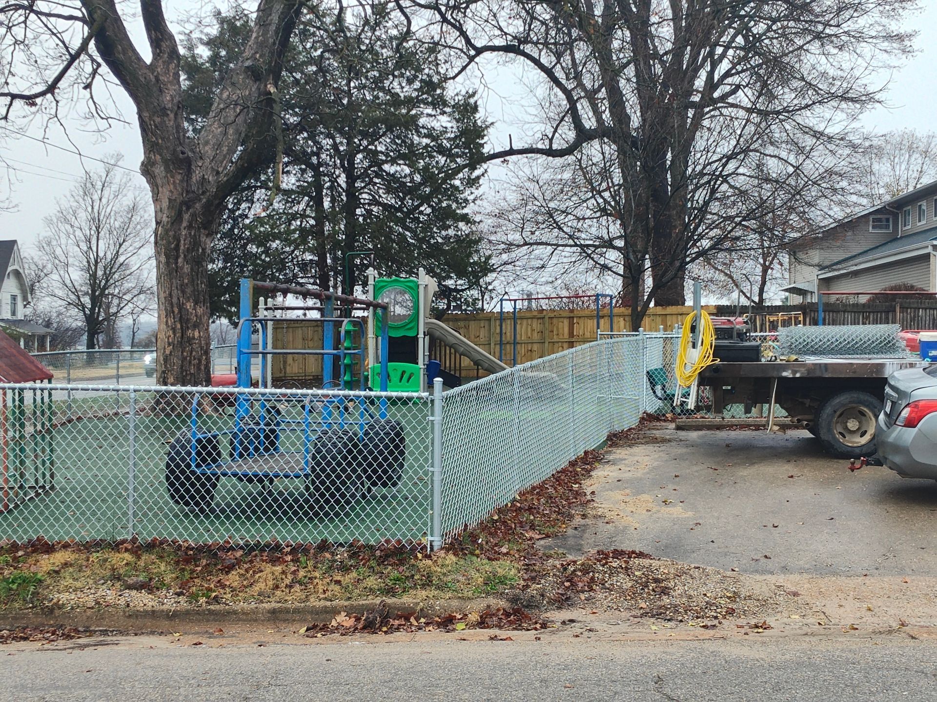 Wooden fence with broken planks, surrounded by greenery and a plant pot.