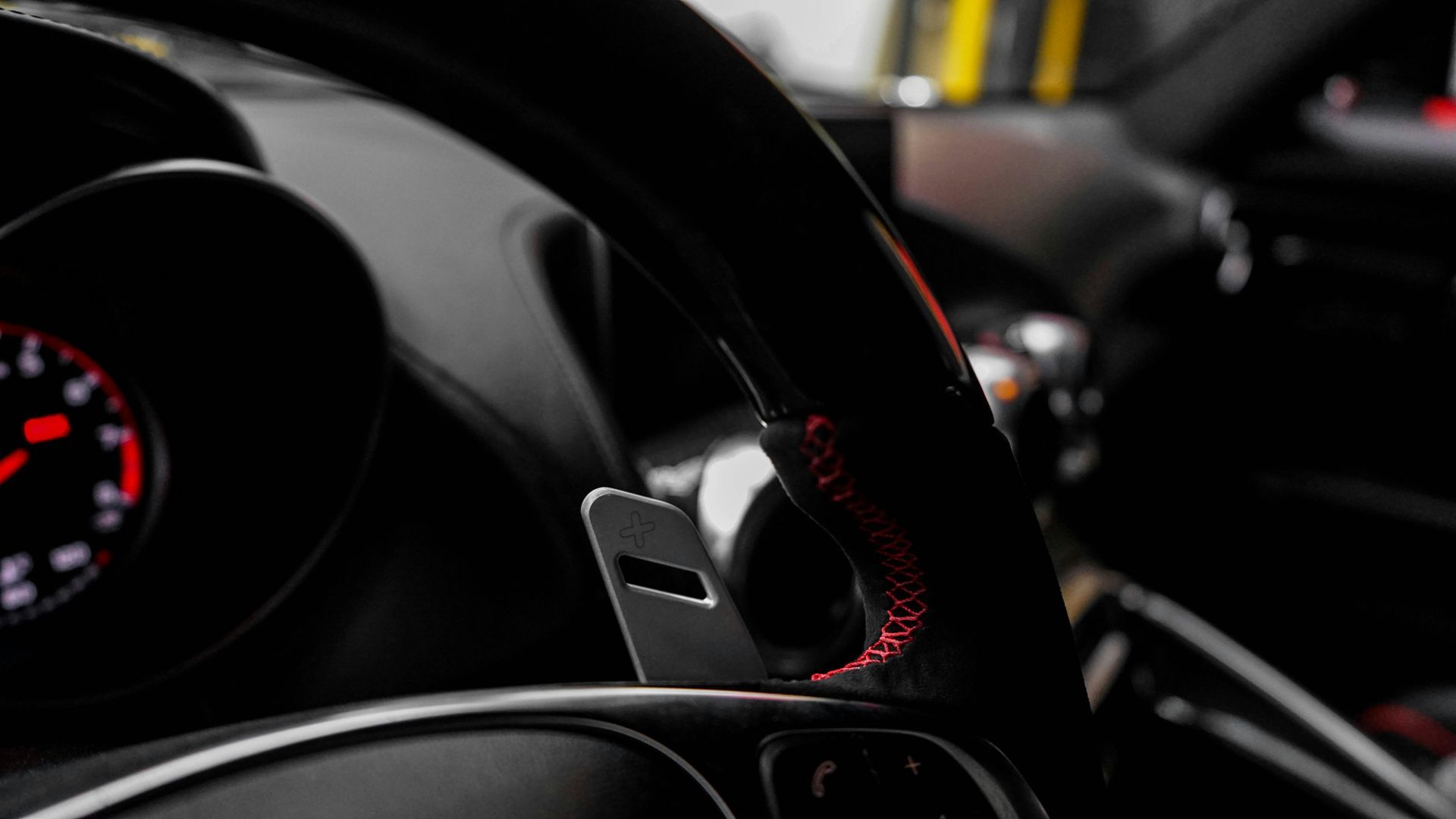A close up of a car steering wheel and dashboard.