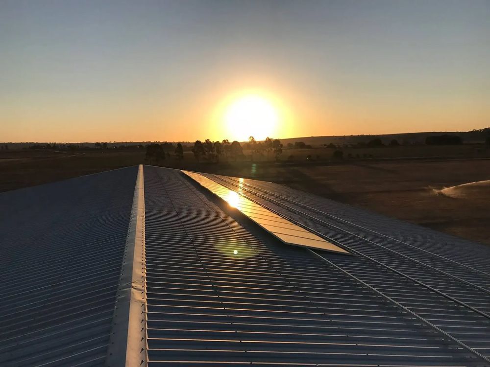 The Sun Is Setting Behind the Roof of A Building With Solar Panel — Solar Blessing in Stanthorpe, QLD