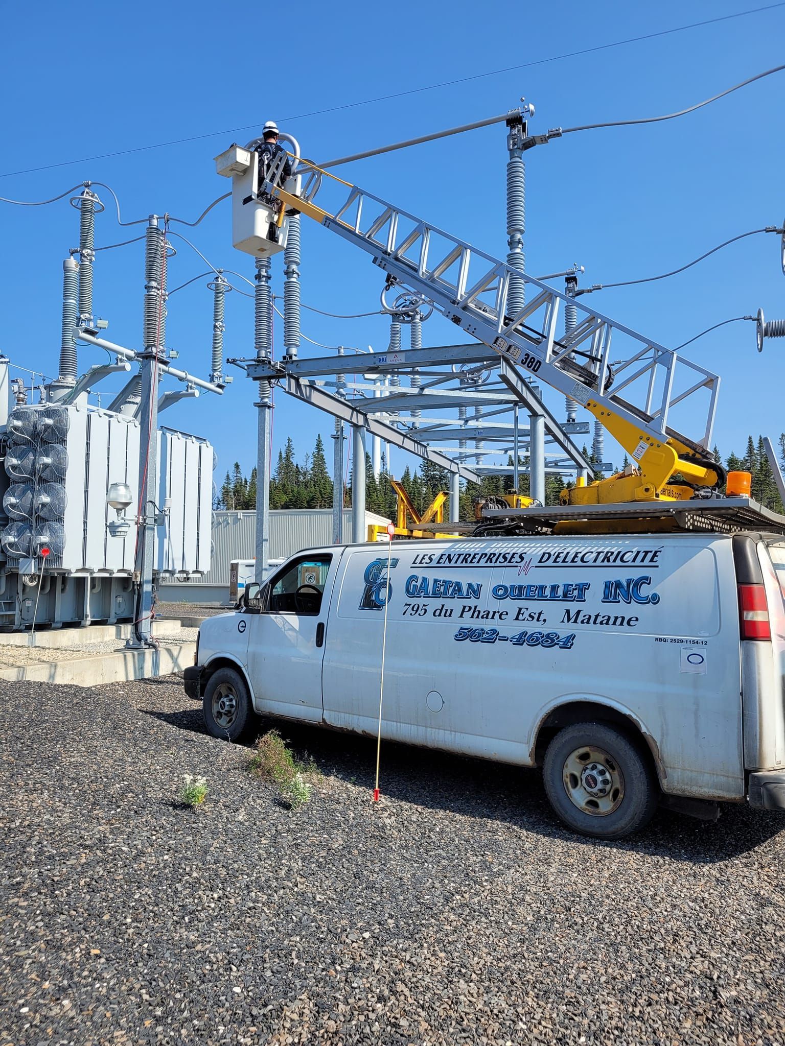 Une camionnette blanche est garée devant une centrale électrique.