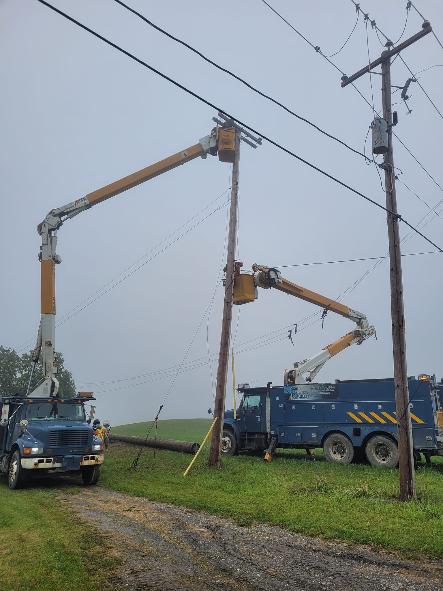 Un camion travaille sur une ligne électrique dans un champ.