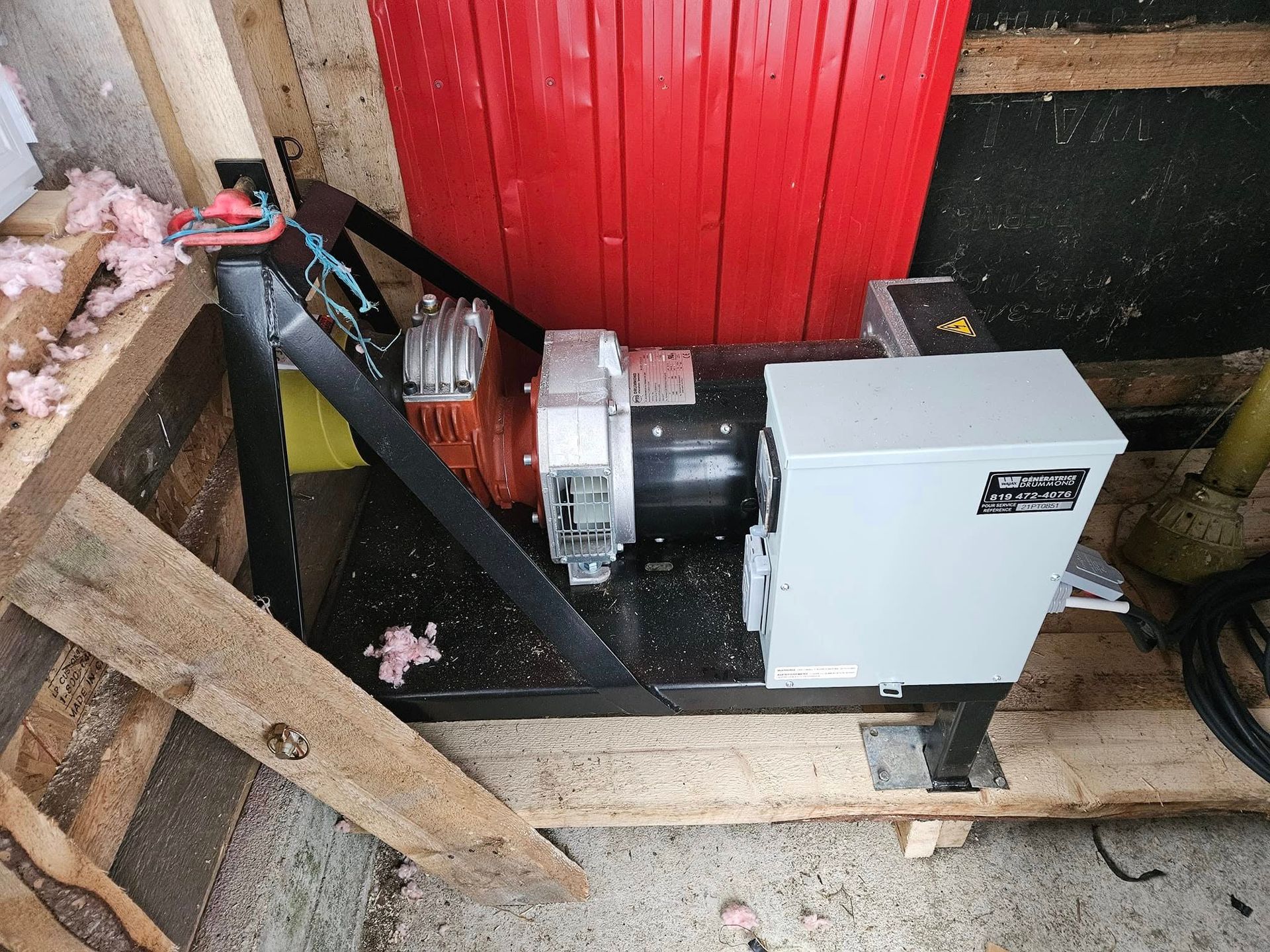 Une machine est posée sur une table en bois devant une porte rouge.