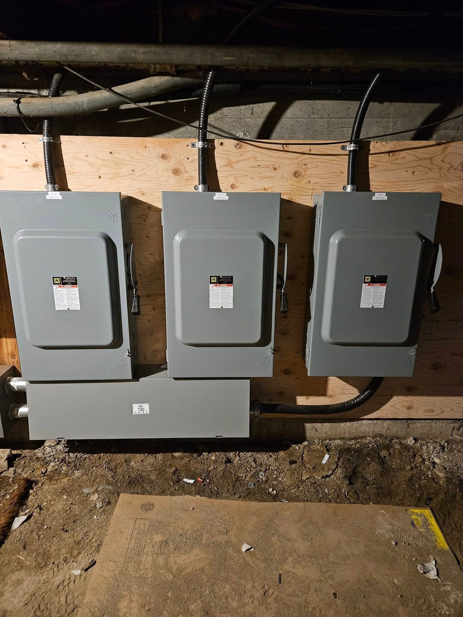 Trois boîtiers électriques sont posés sur un mur en bois.