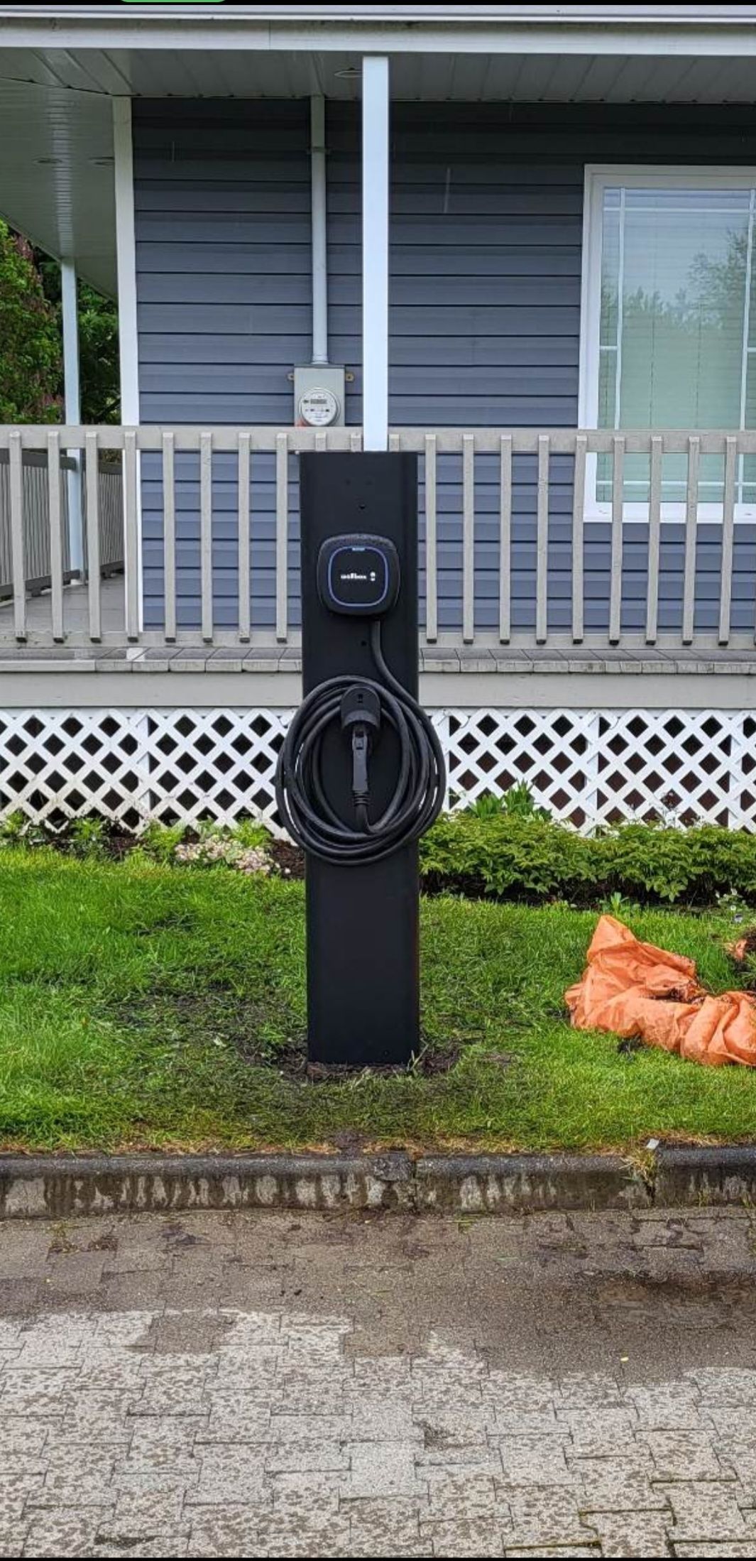 Une borne de recharge Tesla se trouve devant une maison.