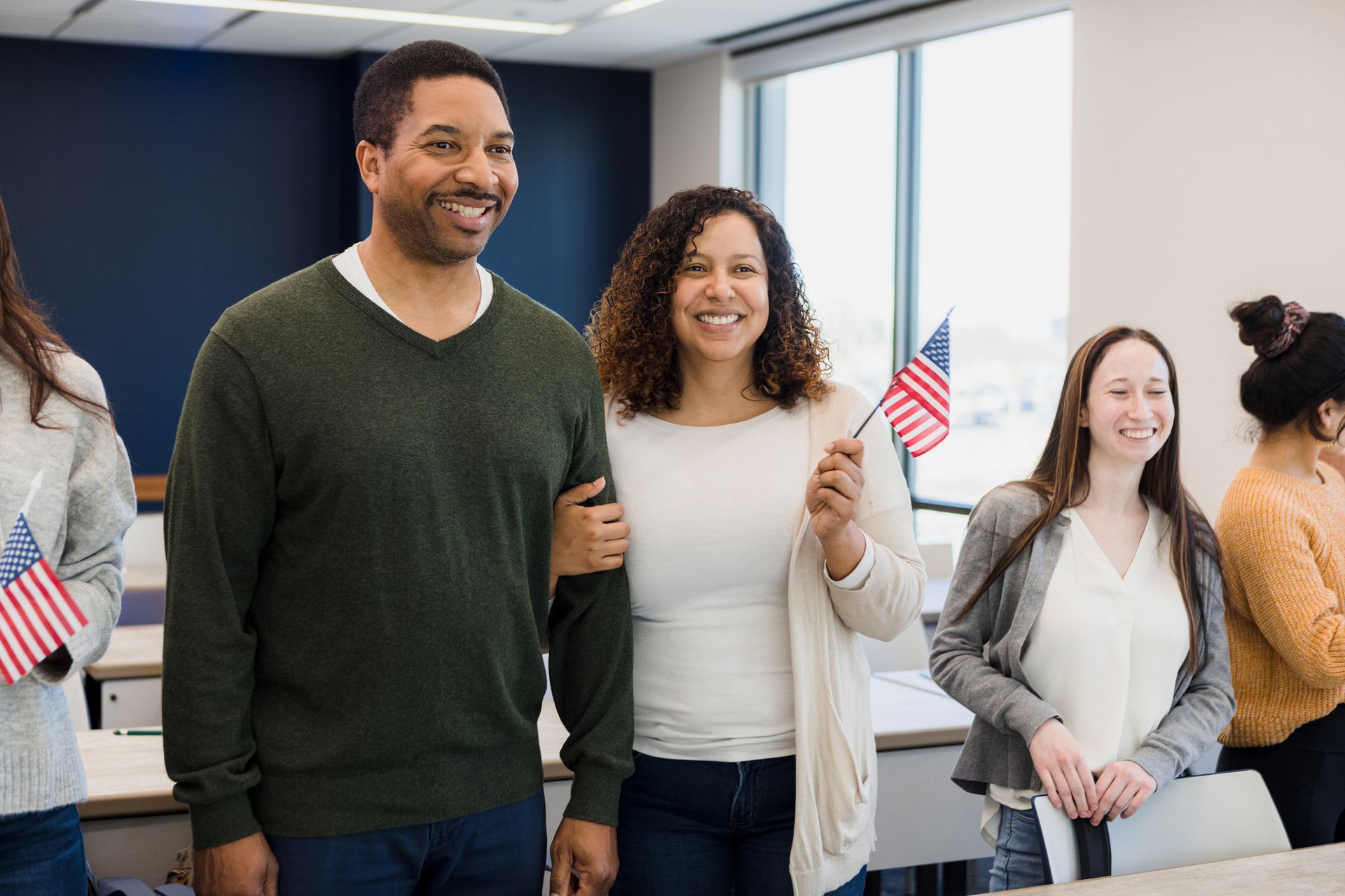 A group of people are standing in a room holding american flags.