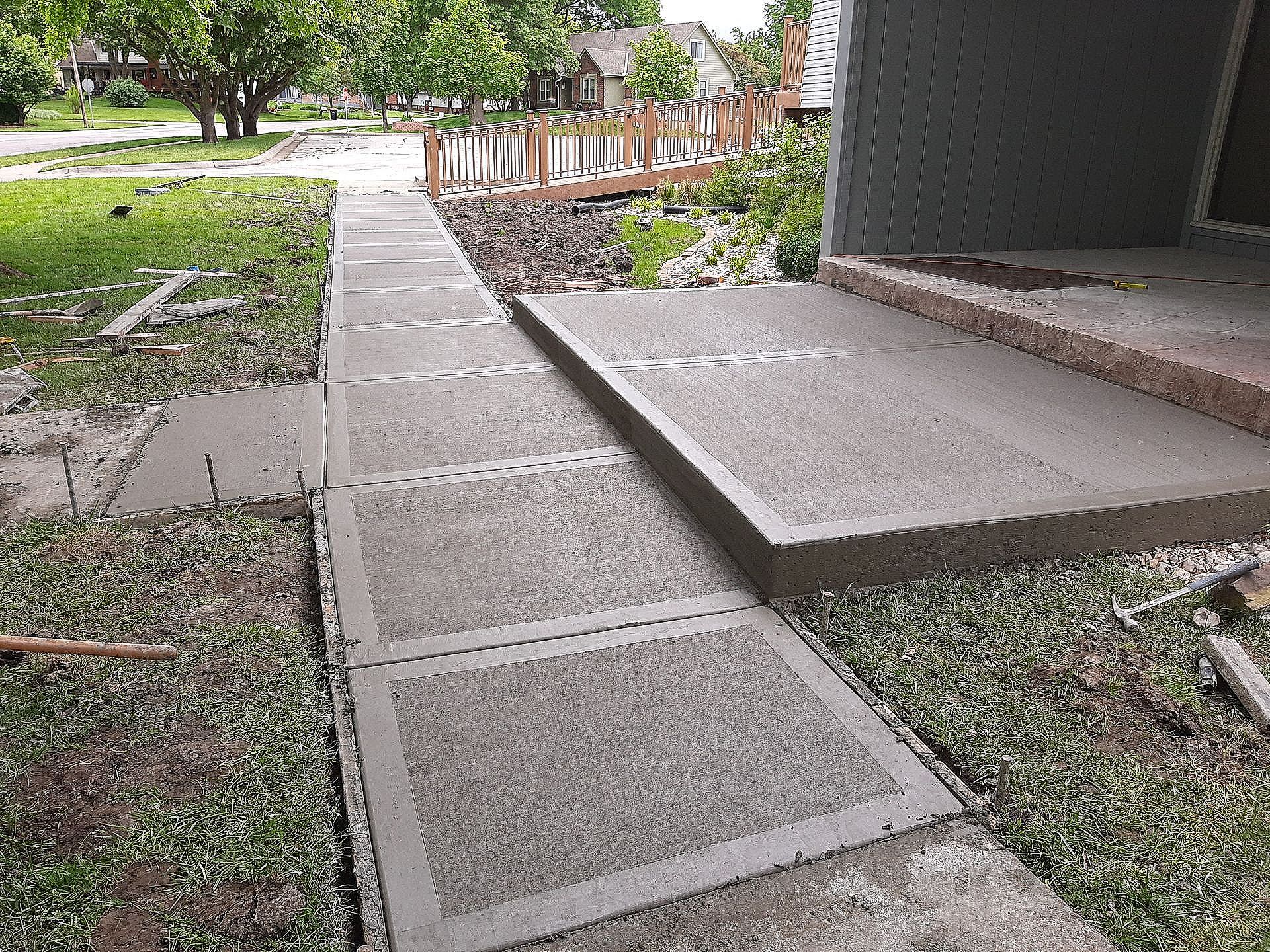 a woman is walking down a sidewalk next to a concrete barrier .