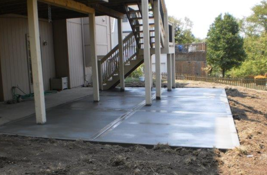 a concrete patio under a house with stairs