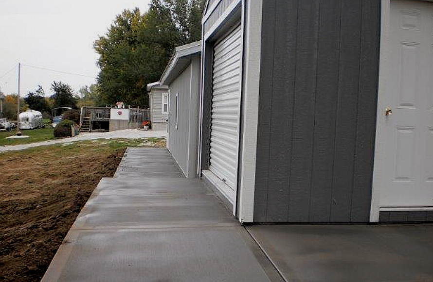 a concrete walkway leading to a garage next to a house