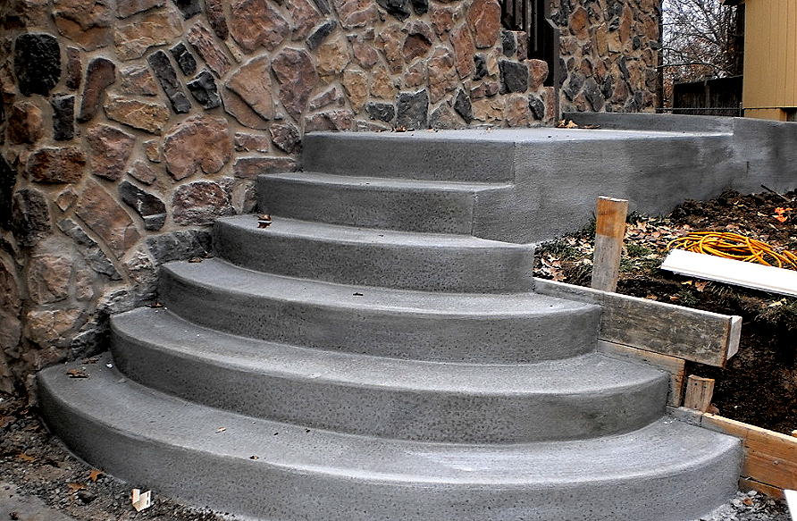 a set of concrete stairs being built in front of a stone wall .