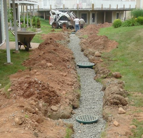 a bobcat is working on a drainage system in a yard