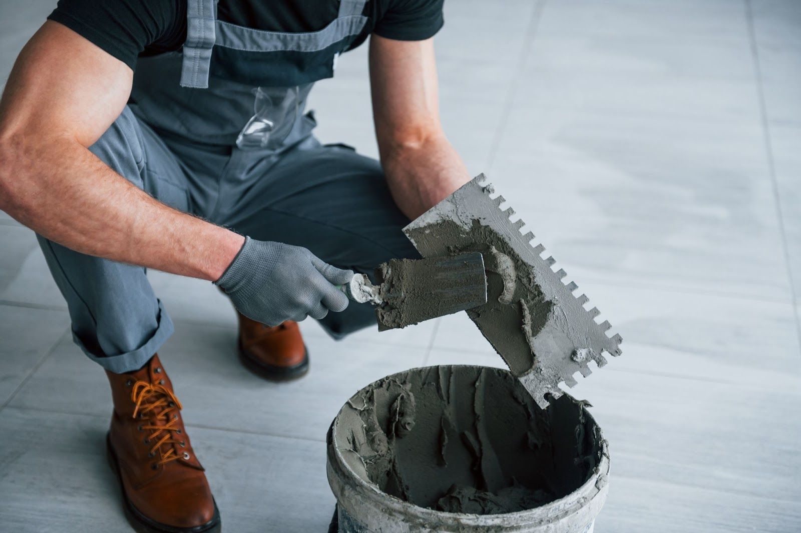 A man is pouring cement into a bucket with a trowel.