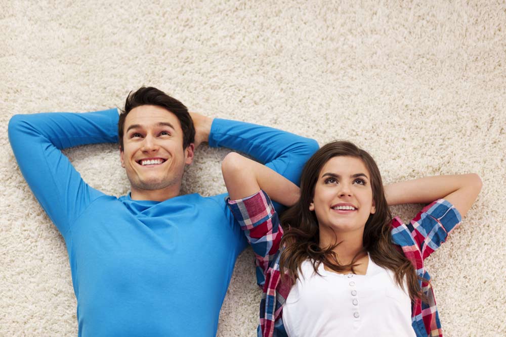 Couple lying on clean carpet after bond cleaning taken place