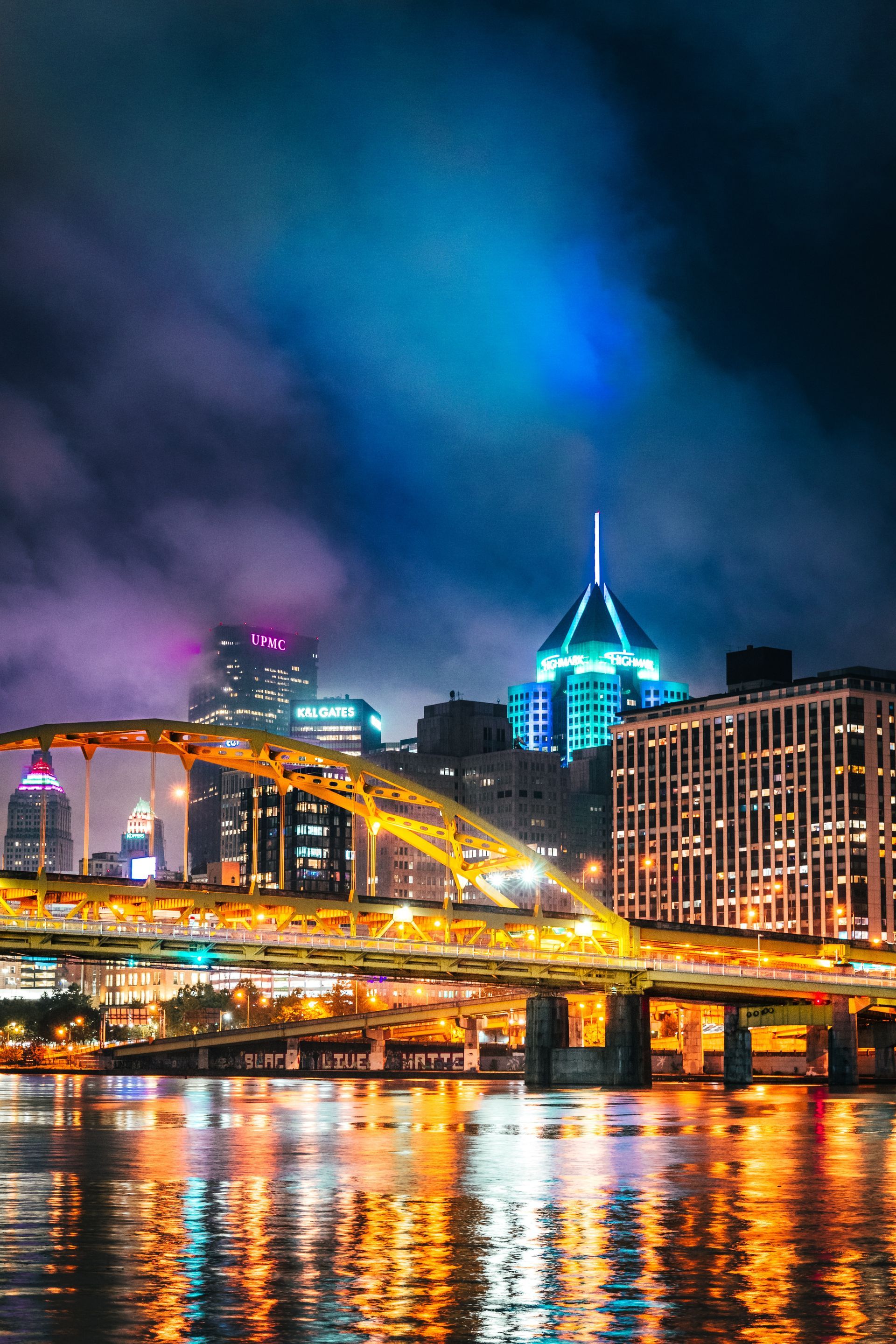 A bridge over a body of water with a city in the background at night.