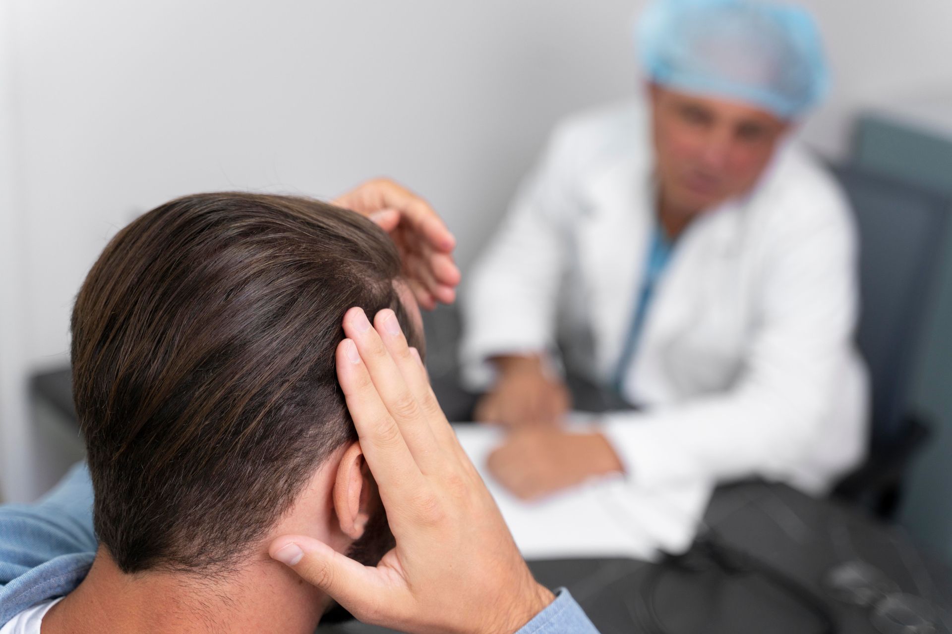 a man has his hand on his head while a doctor looks on