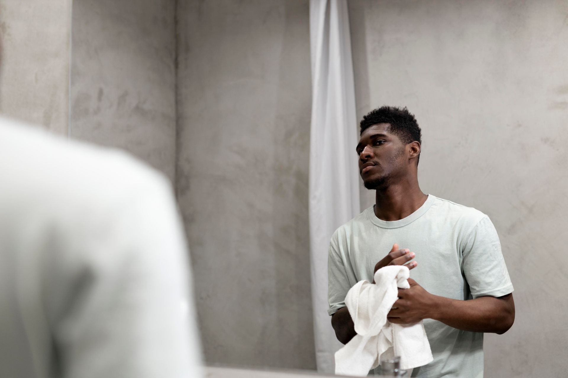 a man is standing in front of a bathroom mirror holding a towel .