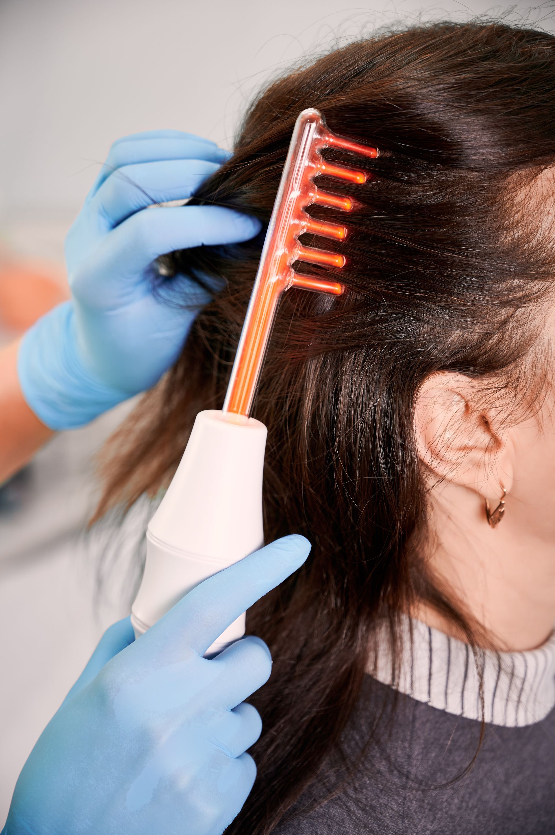 a woman is getting a hair treatment with a comb that has red lights on it