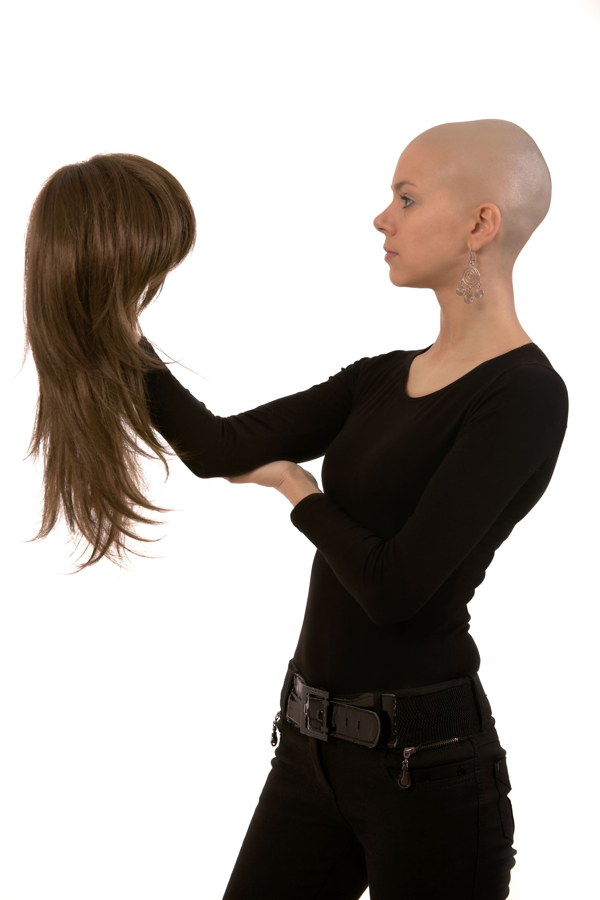 a woman with a shaved head is holding a wig in her hands .