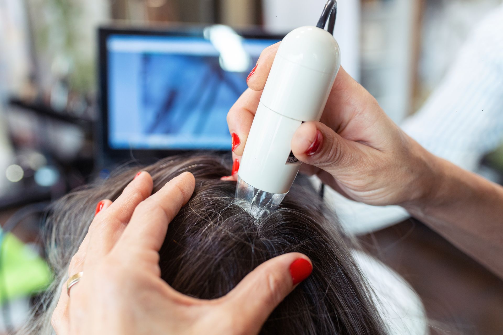 a woman with red nails is examining a woman 's hair with a microscope