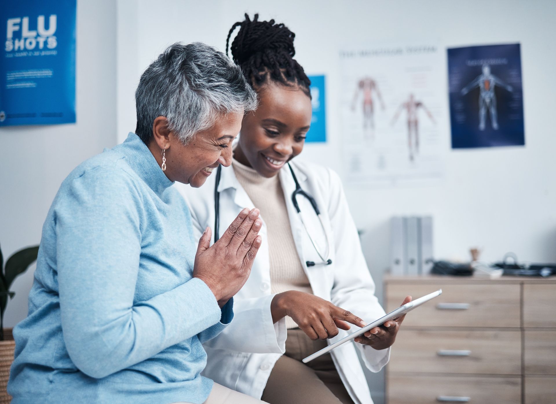 a doctor and patient are looking at a tablet in front of a flu shots poster
