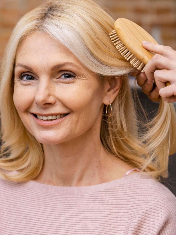 a woman wearing a mask is brushing another woman 's hair